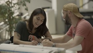 Photo of two students sitting at a table working on a design