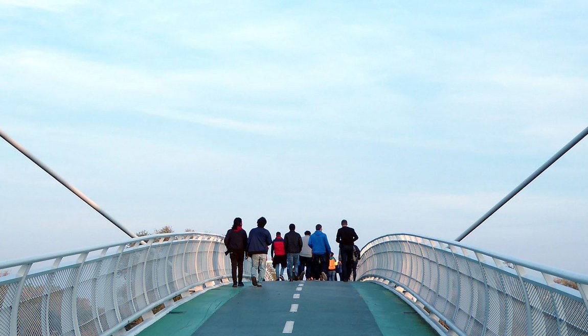 Photo people walking on bridge, blue sky in background