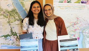 Photo of two people in front of a display board with plans.