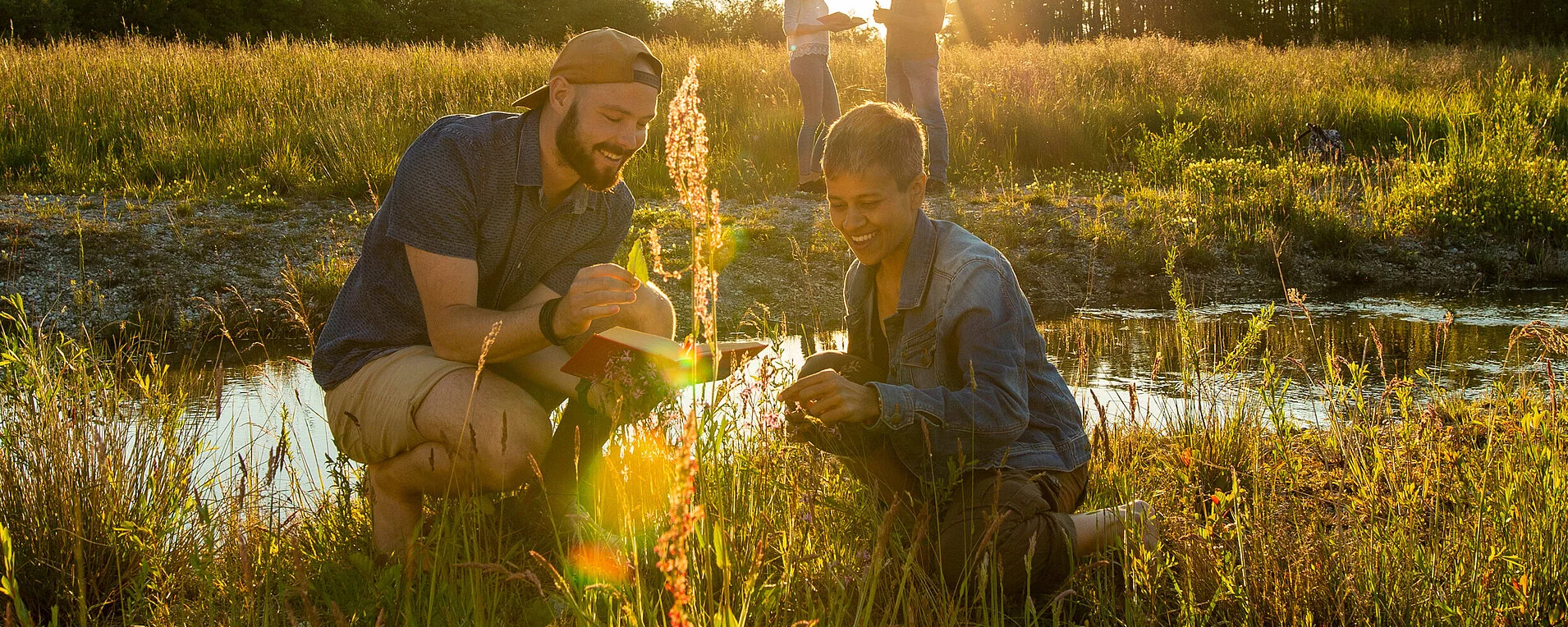 slide - Photo of two students kneeling in a meadow to identify plants