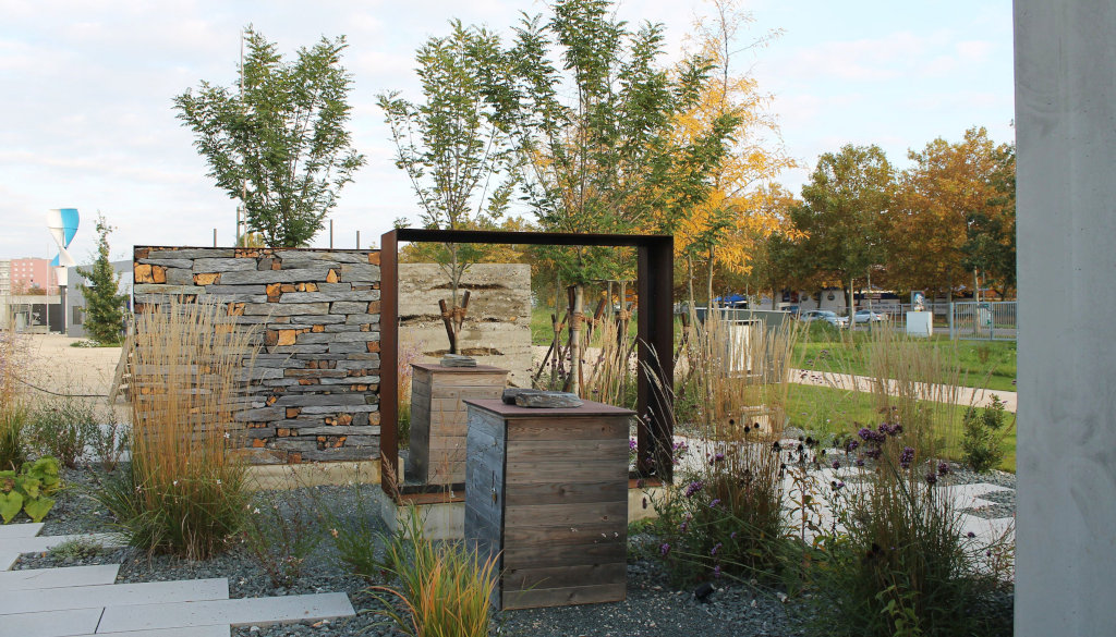 photo garden, pavement with slabs, gravel and grass, art object and wall, background trees